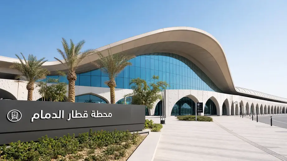 التصميم المعماري الحديث محطة قطار الدمام من الخارج مع لوحة ترحيبية باللغة العربية.